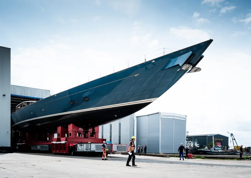 Zero rolls out of Vitters' construction hall in Zwartsluis on a self-propelled modular transporter, her hull already carrying the metallic dark-blue finish and the reverse stem drawn from J-Class lines.