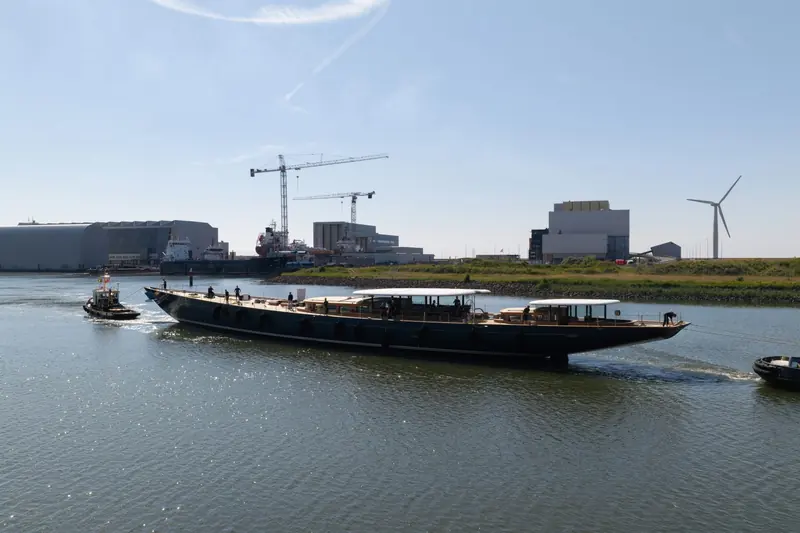 Waterborne for the first time, shipyard cranes and a wind turbine on the skyline - fitting company for a yacht designed to make her own power from wind, sun and speed.