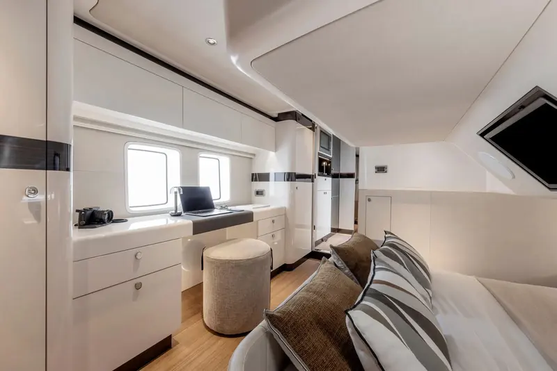 A desk and hull windows in the master. Storage on this model is day boat storage, sized for a weekend rather than a season.