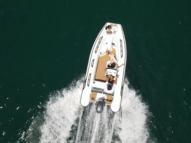 An Alumina tender at speed, planing hard with a full wake astern and two people aboard.