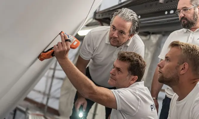 Pinmar technicians work an Awlfair spray filler trial into a superyacht hull ahead of topcoat.