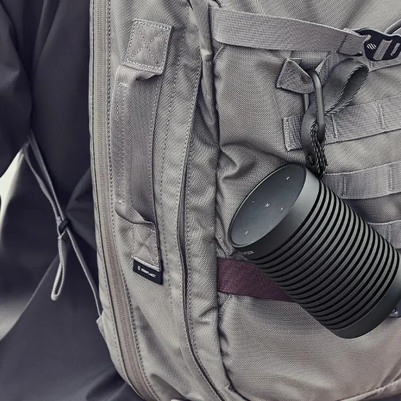The same portable speaker carabinered to a hiking backpack, rated for rock and weather in a way none of the brand's built-in marine systems are.