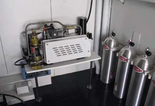A compressor and stacked breathing-air cylinders sit installed in the tender garage aboard the 139ft Oceanco Aspiration, plumbed to a fill station on the bulkhead.