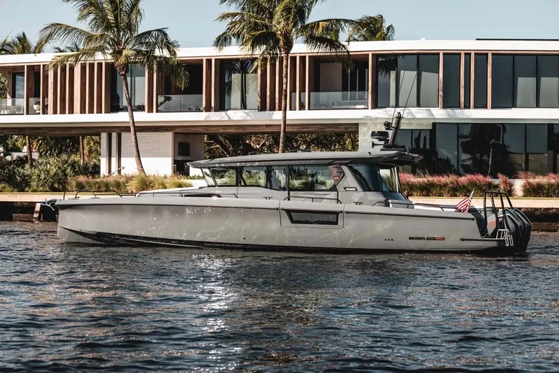 A Brabus Shadow 1500 idles past a waterfront home on the Fort Lauderdale intracoastal, the full 45-foot hull graphic and open helm visible in profile.