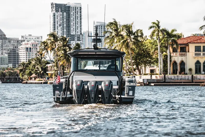 Stern-on against the Miami skyline, the Shadow 1500's triple Mercury Racing 500R outboards clear the water together as she comes off plane, a crew member in a Brabus Marine shirt at the helm.
