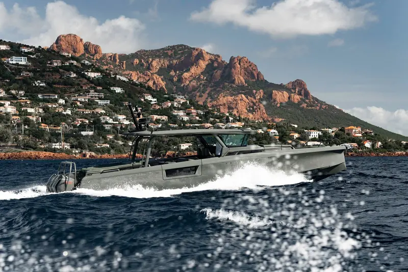 A Shadow 1500 in Sage Green runs hard off the Cote d'Azur, the red rock of the Esterel massif behind her and the double-stepped hull throwing a clean, low wake.