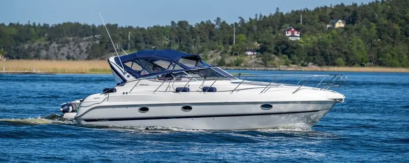 White topsides and a navy bimini catch the sun as a Cranchi cruises through sheltered water.