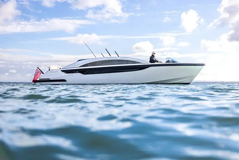 A white limousine tender runs level under a bright sky with her driver alone at the open aft helm.