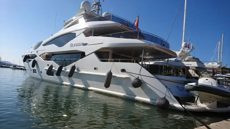 Round Fendertex fenders in dark grey cushion the bow of the motor yacht Elysium alongside, spaced along the topsides ahead of the boarding platform.