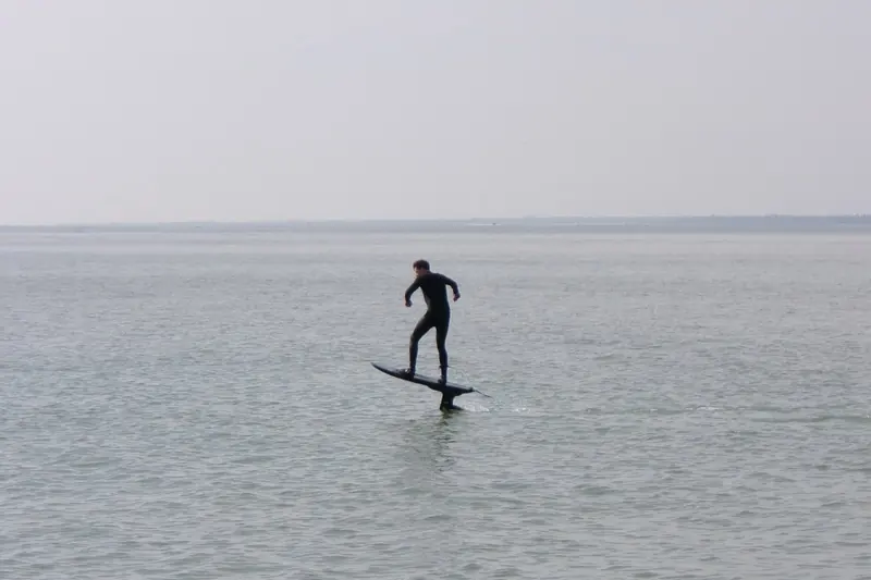 An eFoil in flight off Gurnard on the Isle of Wight, running flat water on a grey afternoon.