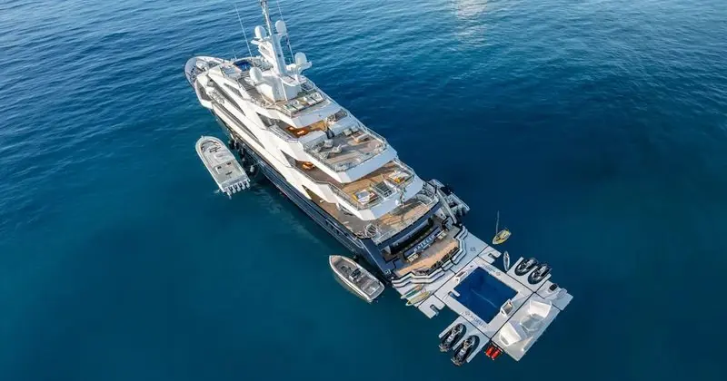 Seen from overhead, a yacht at anchor has a floating platform and tenders made up along her side.