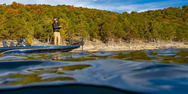 An angler works a fly rod from the bow of a bass boat fitted with a Garmin LiveScope transducer on its own mount at the trolling motor, the real-time forward-looking sonar rig Garmin built its freshwater fishing reputation on.