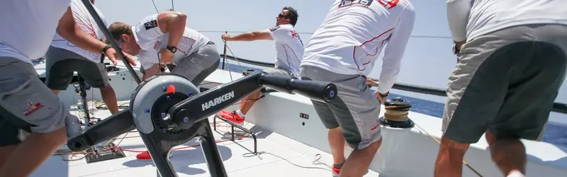 A grinder works a HARKEN-branded pedestal on board the TP52 Provezza. Grand Prix racing is where Harken's winch and pedestal designs are proven before they reach a cruising boat.