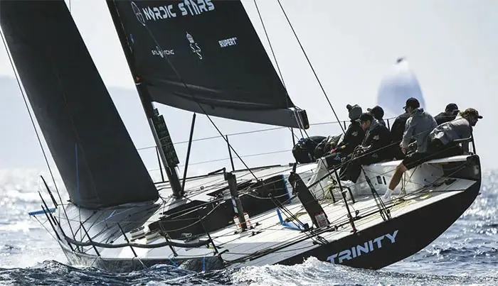 The TP52 Trinity racing upwind, crew hiked out on the rail with deck hardware and travelers under load. Harken has supplied deck gear across the TP52 fleet for two decades.