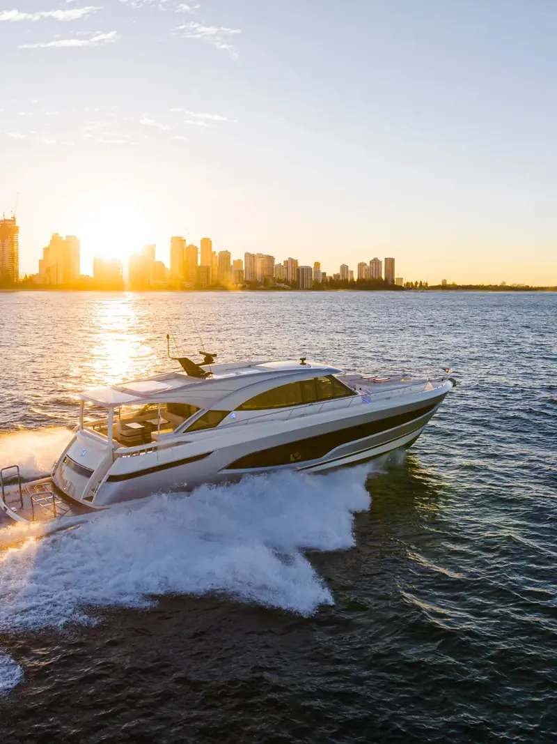 A planing motoryacht running fast off a city waterfront at sunrise, the kind of leisure hull Humphree's transom interceptors and fins are built to keep flat and level at speed.