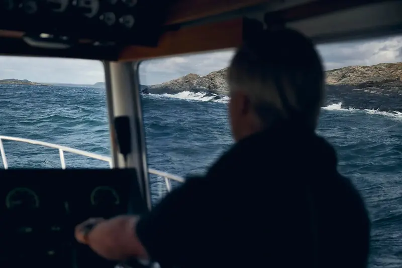 A helmsman drives into a rough Scandinavian sea, hand on the throttle: the pitching, following-sea condition that trim and stabilisation systems exist to take the edge off.