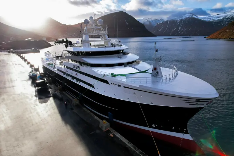 A fishing and processing vessel alongside in the Faroe Islands, photographed for Intellian's case study on ultra-reliable connectivity in the Arctic Ocean, with twin dome antennas mounted above the bridge.