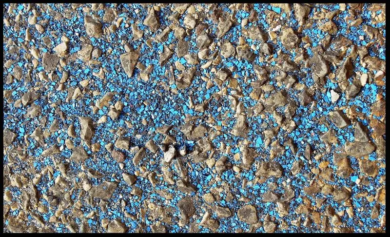 Flakes of old antifouling paint stripped from a sailboat hull before recoating, showing the copper-blue biocide pigment inside the coating.