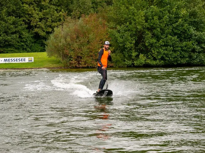 Standing upright, a rider runs a motorised board along the bank of the Messesee at Interboot.