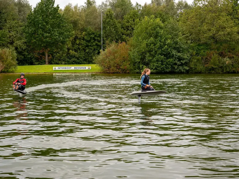 Two boards run a lap of the demo circuit together, an Interboot Messesee sign marking the bank between them.