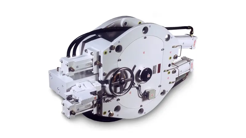 A Naiad hydraulic fin actuator on a factory floor, seen from behind: the tiller wheel for manual centring, the pressure gauges and the paired hydraulic cylinders that swing the shaft through its arc.