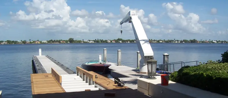 A dock mounted davit stands over a wooden jetty on the Florida Intracoastal, its hook lowered beside a classic runabout tied alongside.
