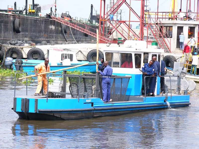 A Scavenger-class harvester crewed and working a harbour, tyres fendering a larger vessel alongside. Northern Lights documents this class of workboat as one of its commercial case studies.