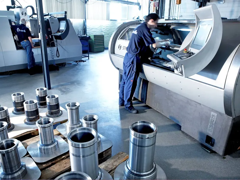 Machinists CNC-finish precision steel sleeves and bushings for stabilizer hardware in the supplier's machine shop.