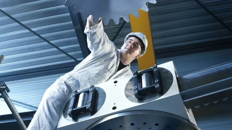 A technician positions a large stabilizer fin flange for installation, the mounting bolts visible around its base.