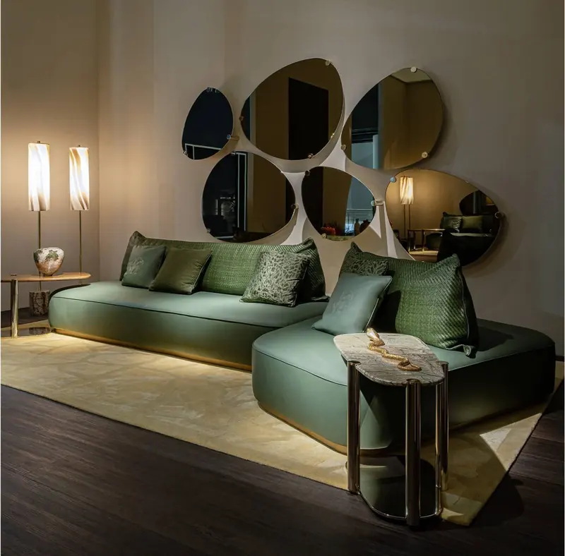 An olive leather sectional against a wall of overlapping bronzed mirrors, shown in Milan in 2026.