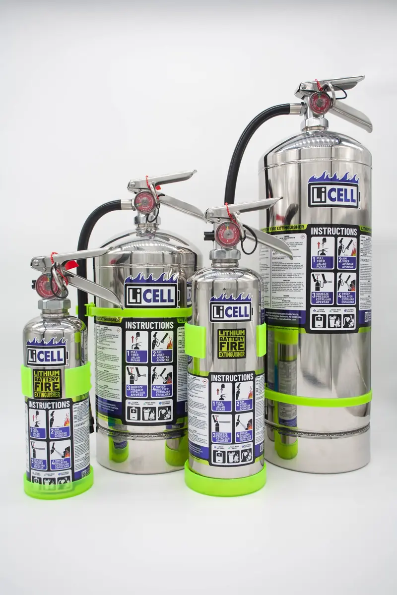 Four polished stainless LiCELL portable extinguishers of graduated sizes stand in a row, each wrapped in a lime green instruction band reading Lithium Battery Fire Extinguisher.