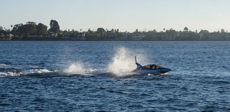 Throwing spray astern, a Seabreacher runs down San Diego Bay past a line of waterfront houses.