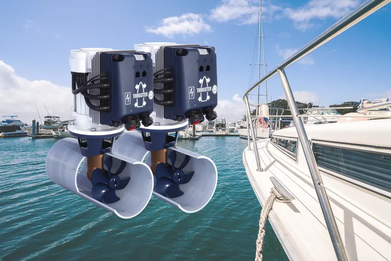 A pair of VETUS bow thruster tunnels and props hang exposed below a yacht's waterline in a marina, the hull lifted for a haul-out.
