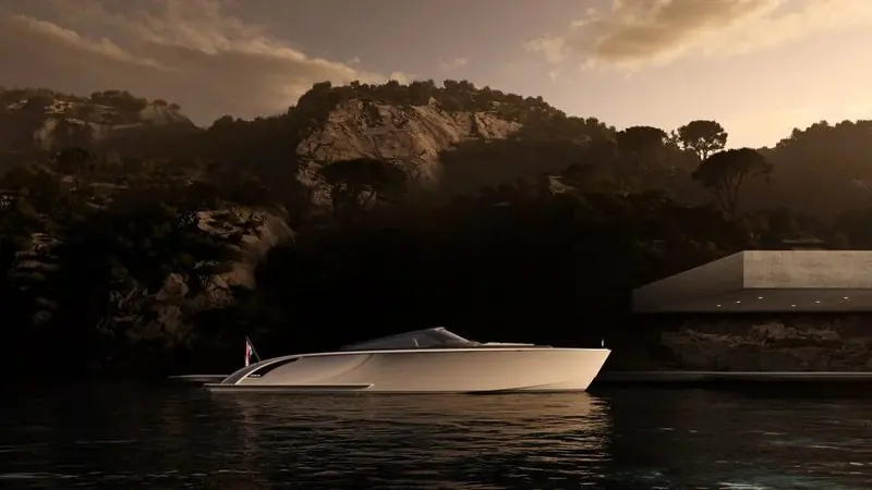At dusk a white Wajer lies off a rocky shore below a low modern house.