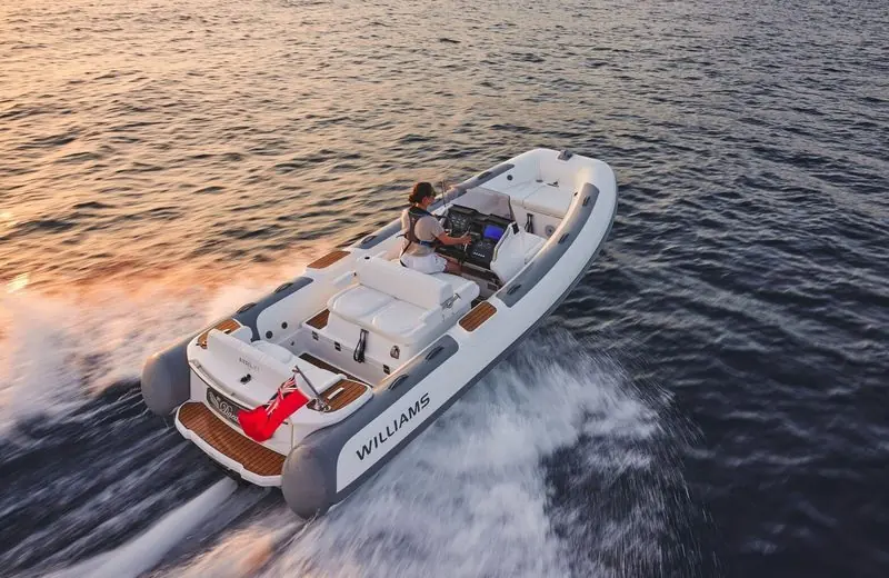 One driver takes a teak-decked Williams tender across open water on the plane.