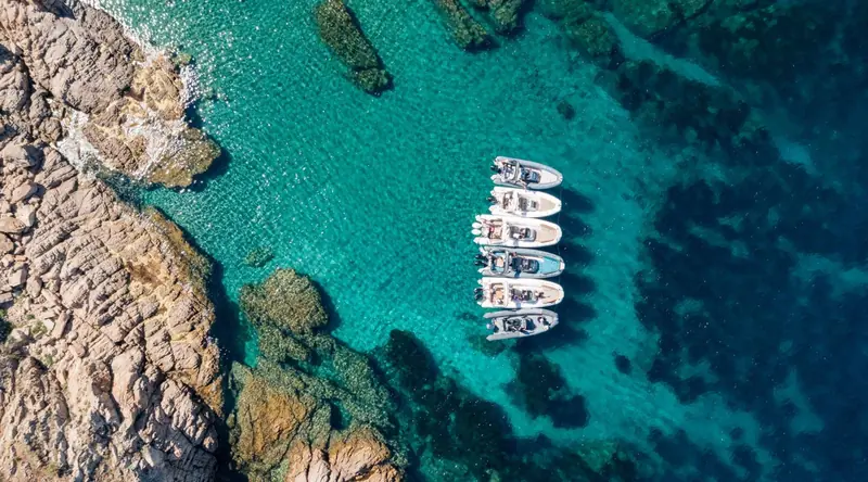 A cluster of Zodiac tenders anchored together in a Mediterranean cove, the fleet size a single yacht's tender garage rarely reaches on its own.