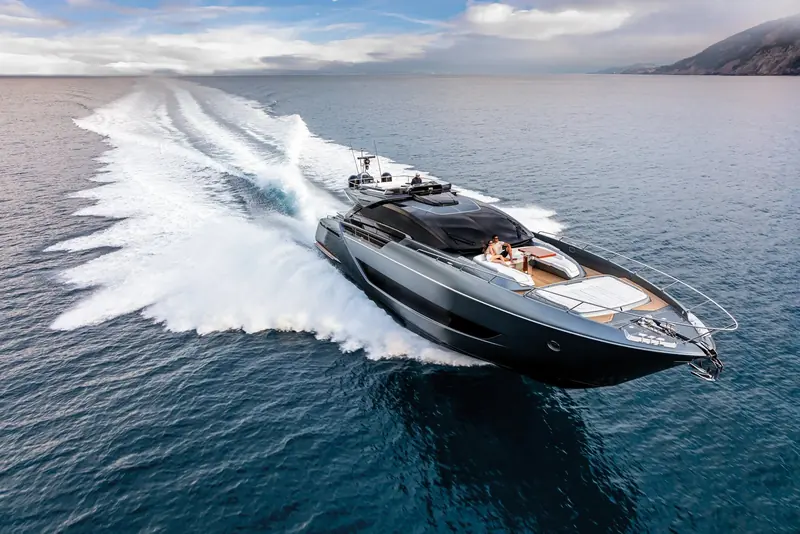 The Riva 88' Folgore running hard, her low black-glass superstructure and flared bow throwing a wide wake.