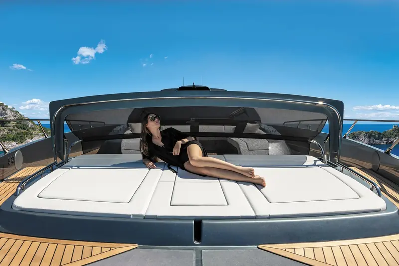 The foredeck sunpad opens the full beam of the bow to lounging, framed by the flybridge overhang above.
