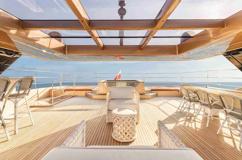 The foredeck lounge and forward jacuzzi, shaded by the retractable glass roof that also frames the flybridge above.
