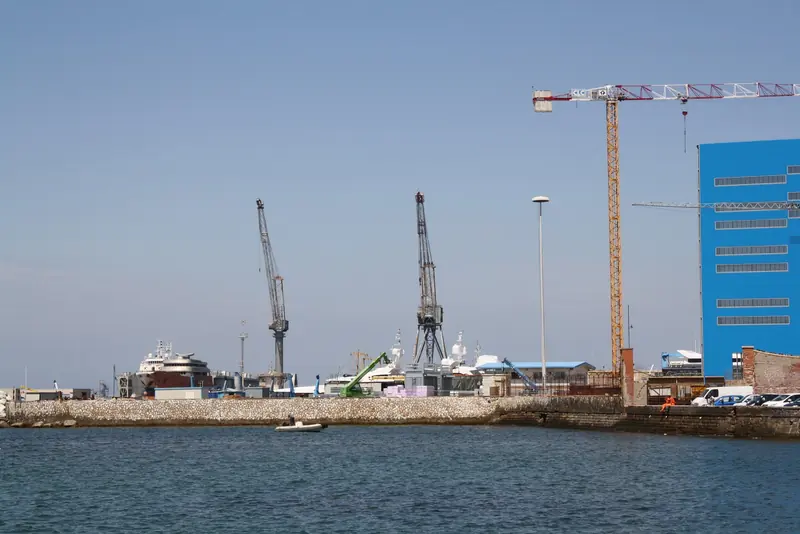Cranes and yacht sheds behind the breakwater at the Benetti shipyard in Livorno