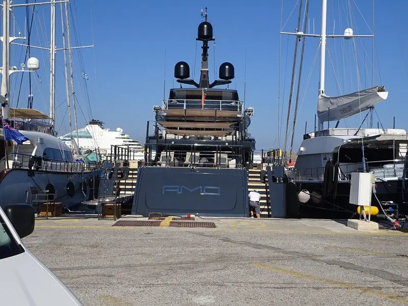 The superyacht Amo berthed stern-to on the quay in the Port of Rhodes, ensigns flying on the yachts alongside