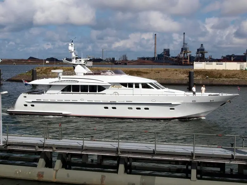 Passing through the lock at IJmuiden, a white motor yacht runs out past the steelworks.