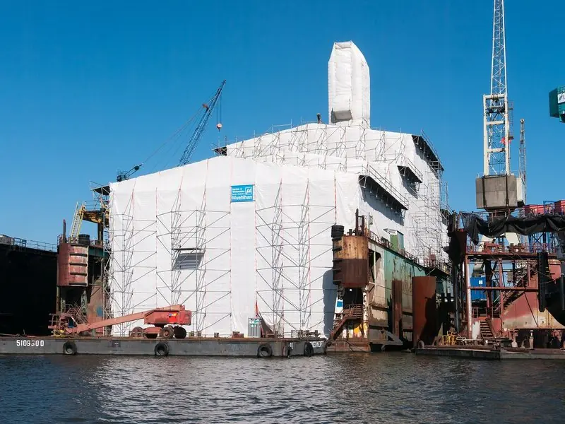 White sheeting and scaffolding hide a hull in the covered dock at the Lurssen yard in Hamburg.