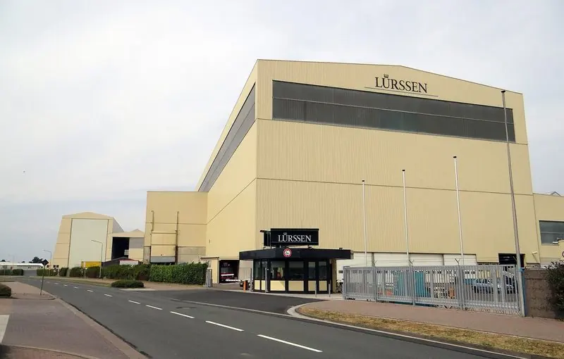 Closed gates and a blank hall front at Lemwerder, where the largest hulls are built out of sight.