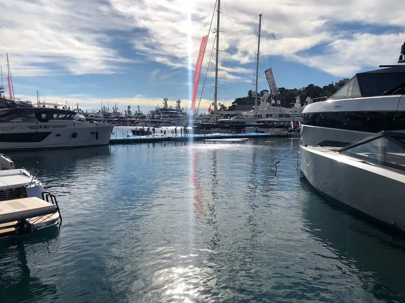 Brokerage banners fly over the floating pontoons between two rows of moored yachts.