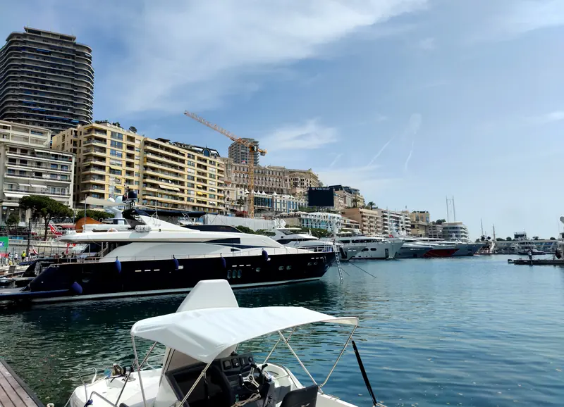 Superyachts line the quay in Port Hercule with the Monte Carlo skyline and its harbourside cranes behind.