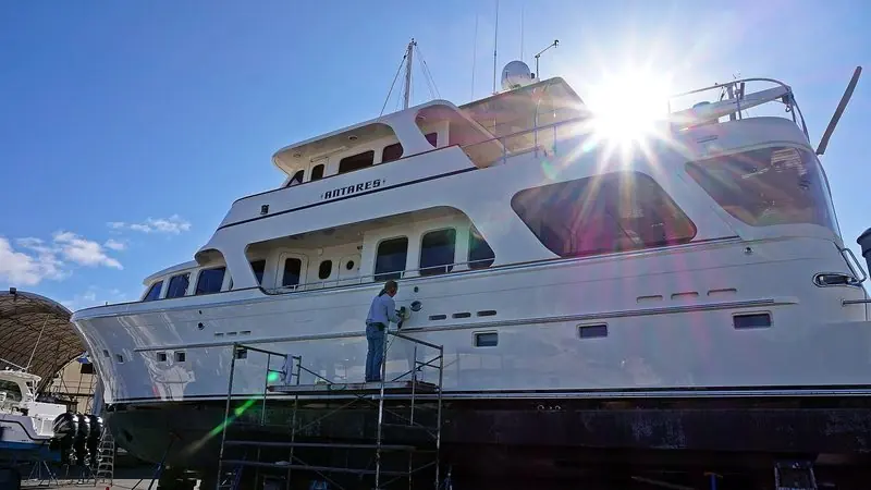 A worker polishes the hull of a motor yacht from scaffolding at a Vancouver Island boatyard