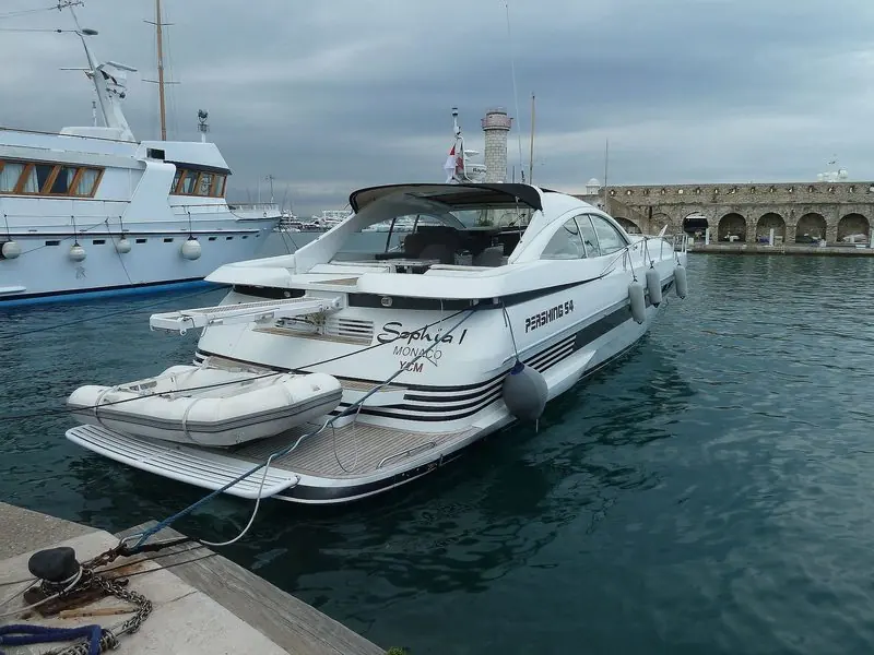 Stern to on a grey day at Antibes, a Pershing 54 carries her tender on the platform.