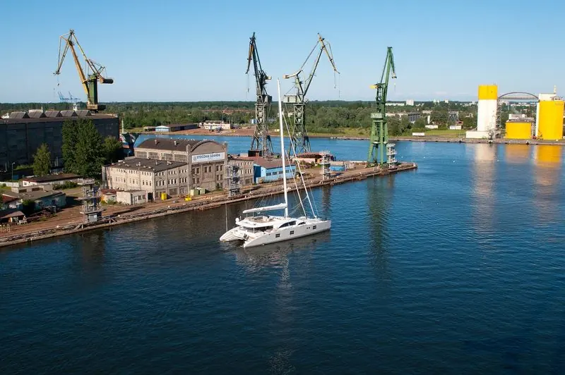 The old Gdansk shipyard cranes stand over a white sailing catamaran on the Martwa Wisla.