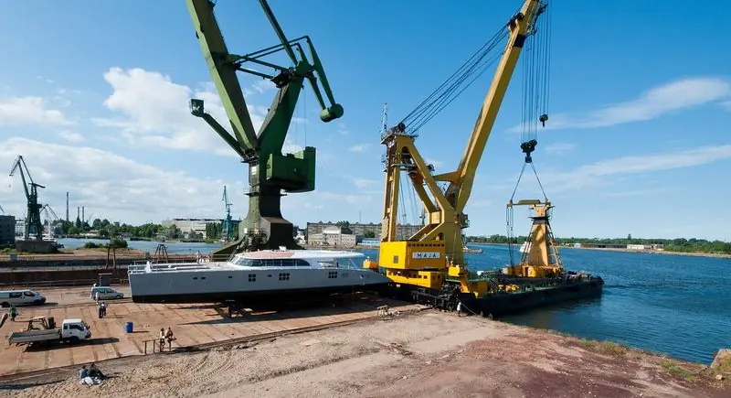 Ready for launch on the yard apron, a catamaran waits beside a floating crane.